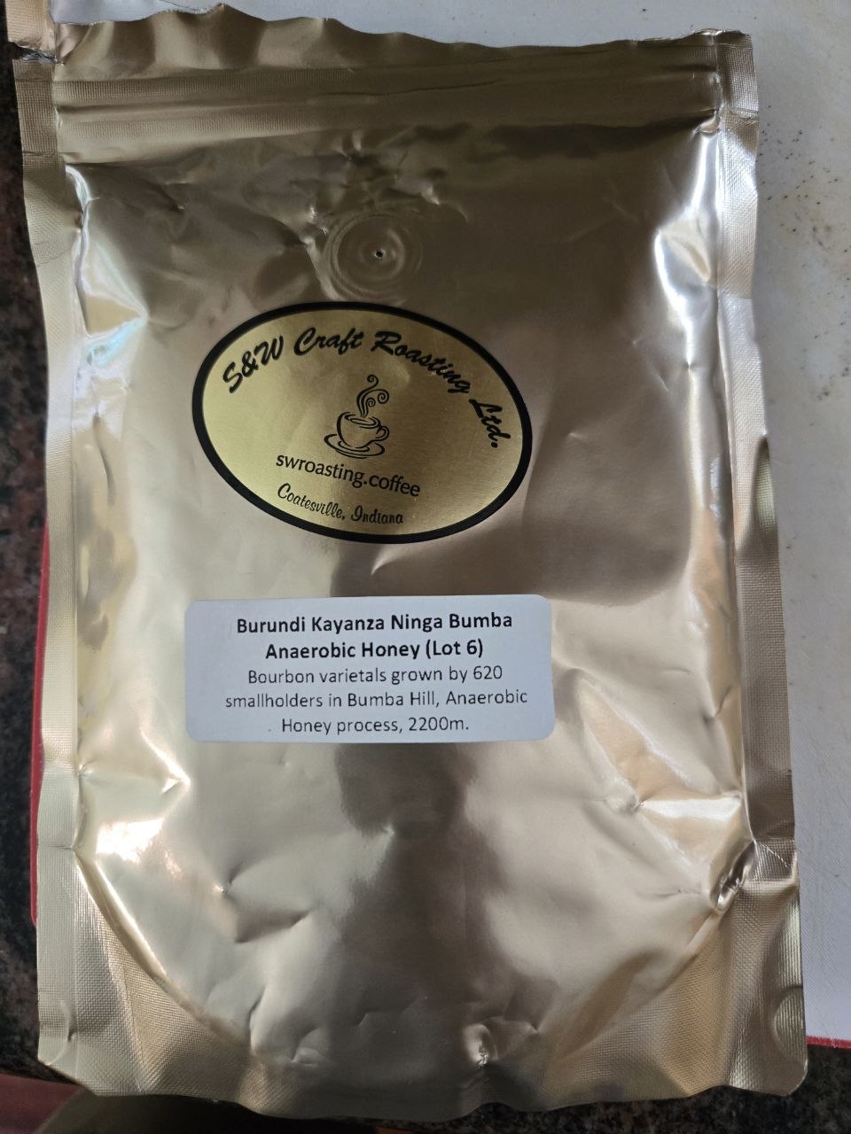 A gold S&W Craft Roasting bag labeled Burundi Kayanza Ninga Bumba Anaerobic Honey, Lot 6, resting on a countertop.